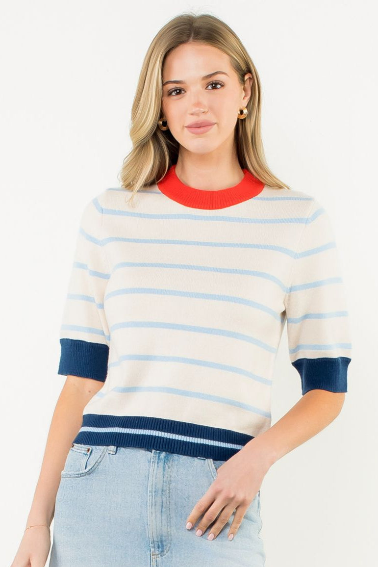Woman wearing a striped sweater and denim skirt on a white background