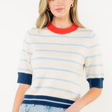 Woman wearing a striped sweater and denim skirt on a white background