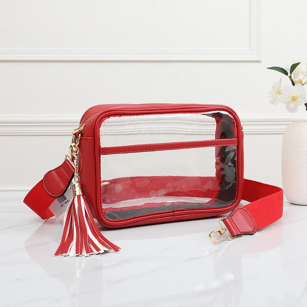 A red crossbody bag with a clear front window, gold-tone hardware, a red tassel charm, and a red adjustable strap.
