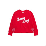A bright red crewneck sweatshirt featuring the words 'Game Day' in white script across the chest, with Gingham bow cutout details on the lower sleeves.