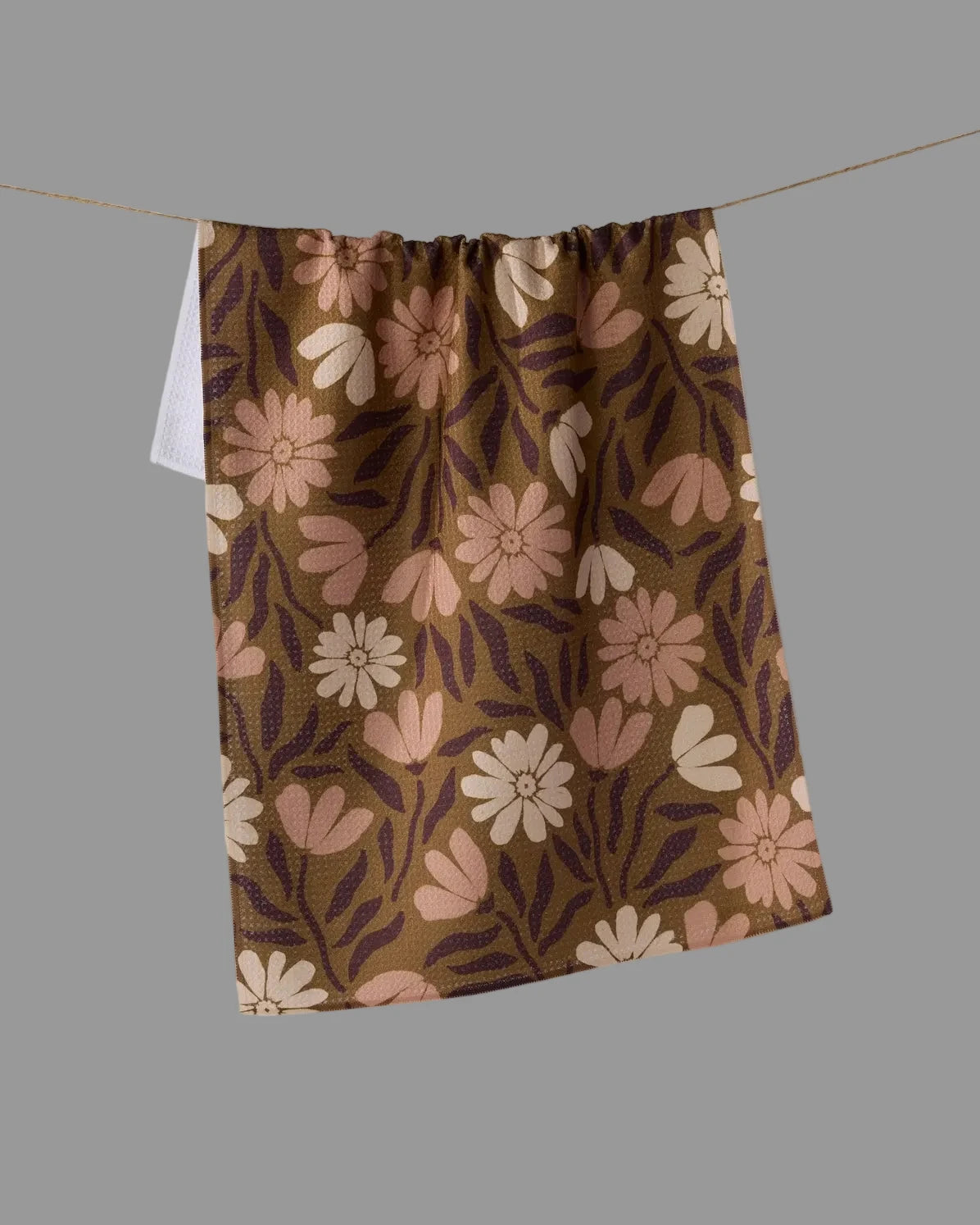 A brown kitchen towel with a retro floral pattern in pink, beige.