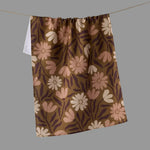 A brown kitchen towel with a retro floral pattern in pink, beige.