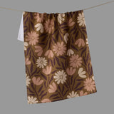 A brown kitchen towel with a retro floral pattern in pink, beige.