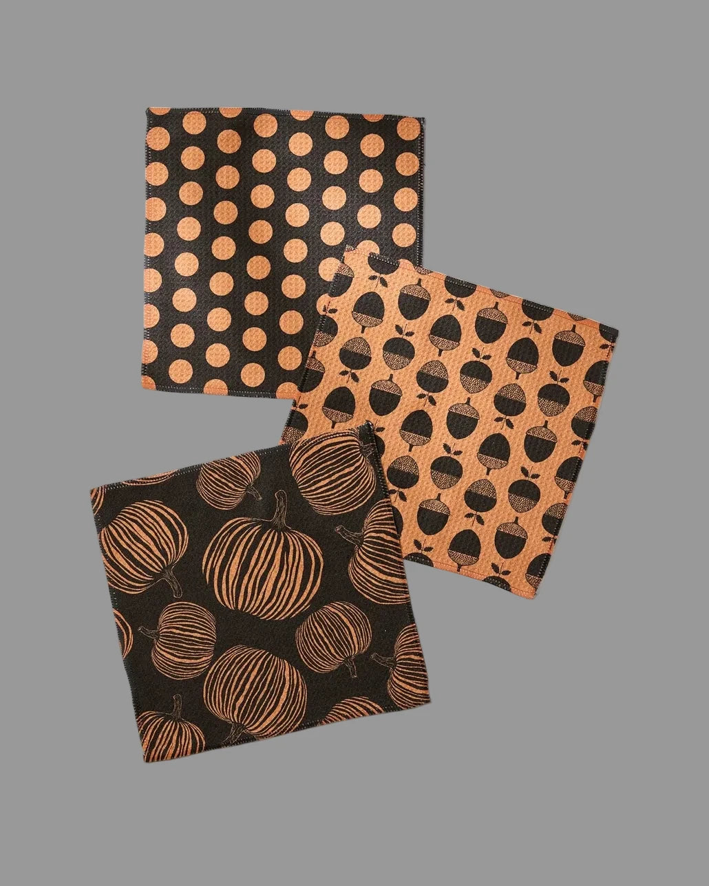 Three Halloween-themed fabric dishcloths with pumpkin, polka dot, and acorn patterns.