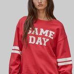Red sweatshirt with cream game day lettering.  Long sleeves with two cream stripes
