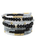 Stack of beaded bracelets with black, white, and gold beads on a white background