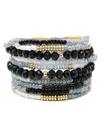 Stack of beaded bracelets with black, white, and gold beads on a white background