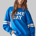 bright blue crewneck sweatshirt with 'GAME DAY' printed in white across the chest and white stripes on the sleeves