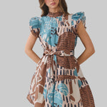 short puff-sleeve dress with a high neck and a tiered skirt, featuring an abstract print in brown, light blue, beige, and black on a plain light background.